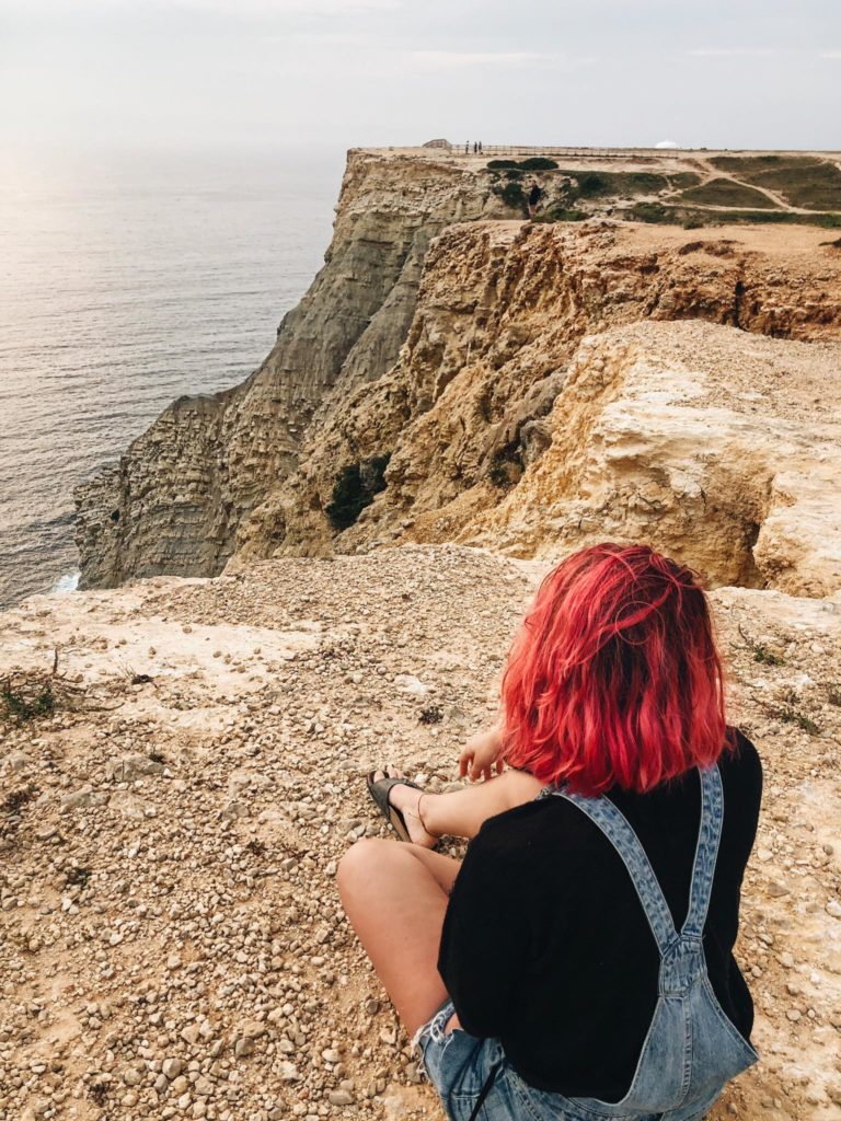 Scogliera e ragazza con i capelli rosa 